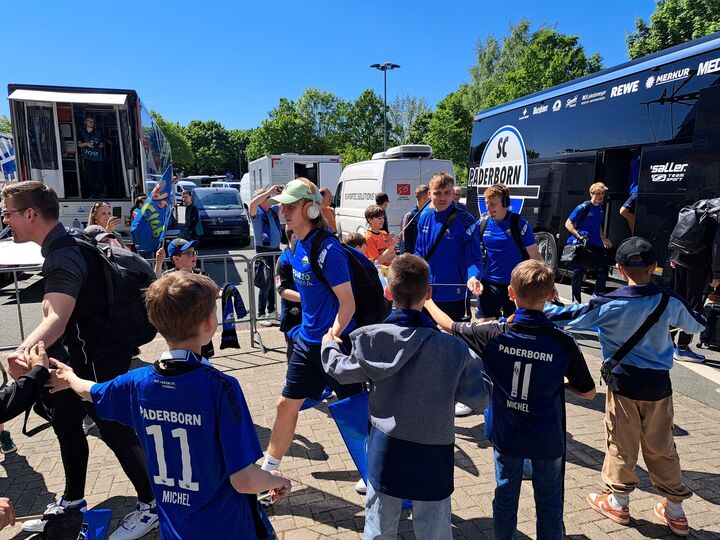 Kinder, welche vor dem Mannschaftsbus des SC Paderborn 07 stehen. Sie klatschen die ankommenden Spieler ab.